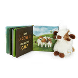 Children's book with cow illustrations and a plush cow toy on a white background